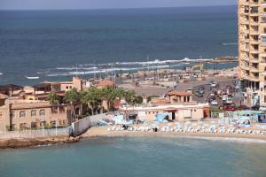 einen Strand mit Stühlen und Gebäuden und das Meer in der Unterkunft Nour 1 in Alexandria