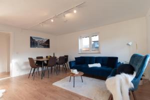 a living room with a blue couch and a table at SMS-Homes I AUSZEIT im BERGBLICKparadies in Sonthofen