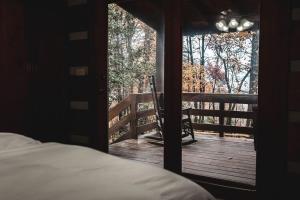 een slaapkamer met een bed en uitzicht op een veranda bij Serenity Ridge Cabin at 36 North - Hot Tub in Purlear