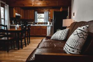 een woonkamer met een bank en een keuken bij Serenity Ridge Cabin at 36 North - Hot Tub in Purlear