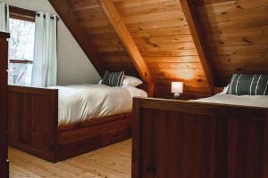 een slaapkamer met 2 bedden in een blokhut bij Serenity Ridge Cabin at 36 North - Hot Tub in Purlear