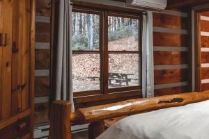 a bedroom with a window in a log cabin at Deer Run Cabin at 36 North - Hot Tub in Purlear