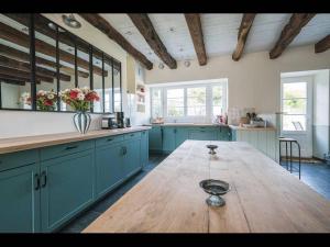 PleurtuitにあるThe House of Anne Dinardの青いキャビネットと木製テーブル付きの広いキッチン