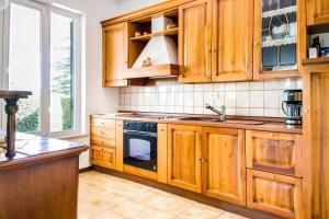 cocina con armarios de madera, fregadero y fogones en Villa Carini with 3000 mq garden & heated pool, en Castelnuovo del Garda