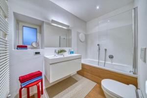 biała łazienka z umywalką i wanną w obiekcie Centrally located apartment with parking space w mieście Caldaro