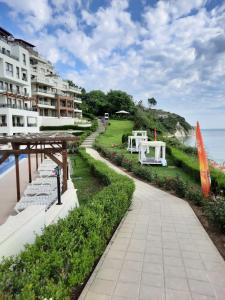 einen Fußweg neben einem Gebäude und dem Meer in der Unterkunft Byala Vista Cliff Apartments in Byala