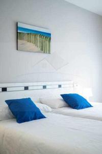 1 cama con almohadas azules y una foto de playa en Apartamento Juan XXIII, en Gijón