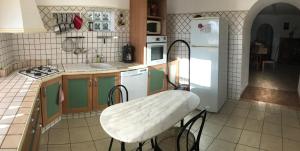 a kitchen with a table and a white refrigerator at GITE DE LA FONTAINE 