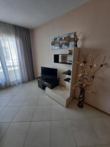 een woonkamer met een televisie en een vaas met bloemen bij Byala Vista Cliff Apartments in Byala