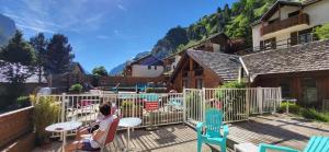 une femme assise à une table sur une terrasse avec des chaises dans l'établissement Chez Philippe - Appartements et Chalets - Panoramic Village vue Glaciers, à La Grave