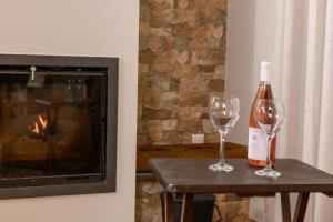 a bottle of wine and two glasses on a table next to a fireplace at Kyra’s House in Neraïdochóri