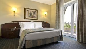 een hotelkamer met een bed en een groot raam bij SANA Rex Hotel in Lissabon