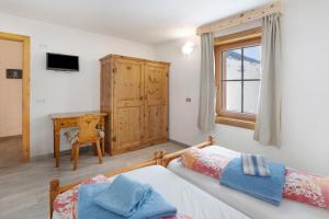 1 dormitorio con 2 camas, escritorio y ventana en Appartamento Vacanze Matteo, en Livigno