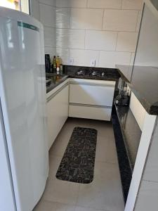 a kitchen with white appliances and a black and white rug at Casa nova com 3 quartos, equipada com Ar Condicionado, TV, Internet e Área de Lazer Completa - Boiçucanga in Boicucanga