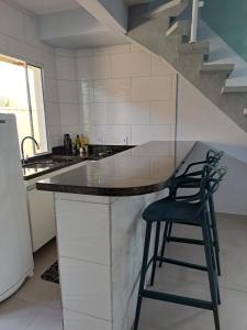 eine Küche mit einer Theke mit zwei Hockern in der Unterkunft Casa nova com 3 quartos, equipada com Ar Condicionado, TV, Internet e Área de Lazer Completa - Boiçucanga in Boicucanga