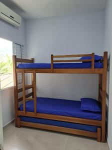 聖塞巴斯蒂昂的住宿－Casa nova com 3 quartos, equipada com Ar Condicionado, TV, Internet e Área de Lazer Completa - Boiçucanga，客房设有三张双层床,配有蓝色床单