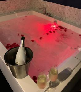 una vasca da bagno con una bottiglia di vino e due bicchieri di L'Eclipse maison romantique avec Jacuzzi 