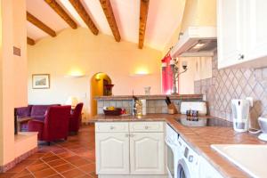 a kitchen with white cabinets and a living room at Campu Latinu in Lama