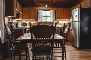 eine Küche mit einem Holztisch mit Stühlen und einem Kühlschrank in der Unterkunft Creekside Overlook at 36 North Cabin - Fireplace in Purlear