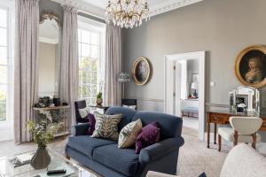 a living room with a blue couch and a chandelier at The Royal Crescent Hotel & Spa in Bath