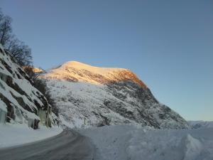 a road covered in snow next to a mountain at Lunheim in Geiranger in Geiranger