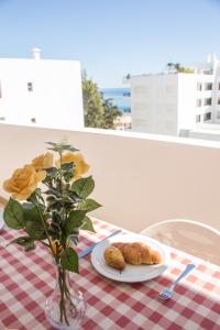 a table with a plate of food and a vase with flowers at Amazing and Cosy Apt near the Beach ByCentralgarve in Quarteira