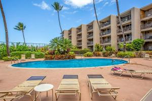 a swimming pool with lounge chairs and a resort at Hale Ono Loa Condo in Kahana