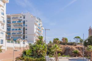 een groot wit gebouw met palmbomen ervoor bij FARO PUERTO ESTEPONA in Estepona