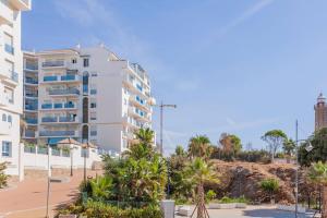 duży biały budynek z palmami przed nim w obiekcie FARO PUERTO ESTEPONA w mieście Estepona