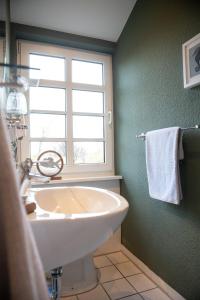 ein Bad mit einem weißen Waschbecken und einem Fenster in der Unterkunft Das Anni's in Wangerland