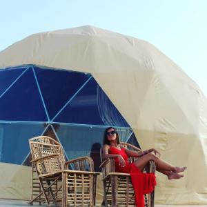 a woman in a red dress sitting in a tent at Warm bubbles Wadi Rum in Wadi Rum