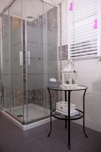 La salle de bains est pourvue d'une douche en verre et d'une table. dans l'établissement La Casa dei Nonni sul Garda, à Peschiera del Garda