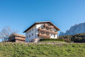 a building on a hill with a mountain in the background at Apartment Völs Gfliererhof in Vols am Schlern