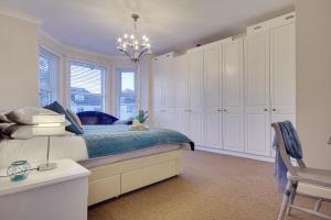 a bedroom with a bed with white cabinets and a chandelier at Beach Way House in Southbourne