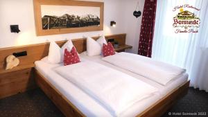 ein Schlafzimmer mit einem großen weißen Bett mit roten Kissen in der Unterkunft Hotel-Gasthof-Sonneck in Reit im Winkl