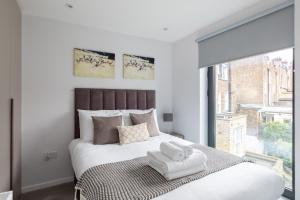 homely - Central London Camden Penthouse Apartment في لندن: غرفة نوم بيضاء مع سرير كبير مع نافذة