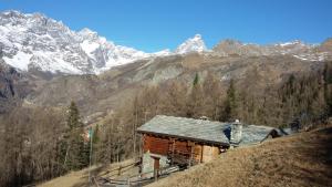 a cabin on a hill with mountains in the background at BAITA Ancienne Bergerie in Valtournenche