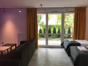 グダニスクにあるLa Petite APARTMENTSのベッド2台、ソファ、窓が備わる客室です。