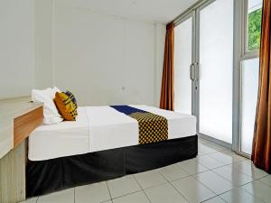 a bedroom with a bed and a large window at SUPER OYO 2190 Alamanda 7 Syariah in Bandung