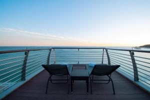 een tafel en stoelen op een balkon met uitzicht op de oceaan bij SANA Sesimbra Hotel in Sesimbra