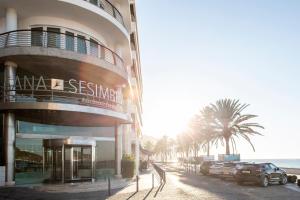 a building with cars parked in front of the ocean at SANA Sesimbra Hotel in Sesimbra