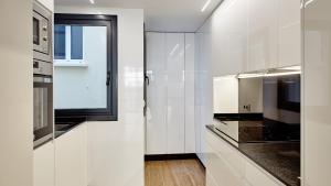 a kitchen with white cabinets and a window at Cíes Luxury Suitel Lily Rodsen - Love your Stay in Vigo