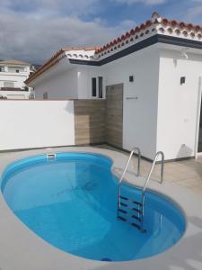 a swimming pool in front of a house at Villa Alexander in Puerto de Santiago