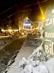 a snow covered street sign in front of a house at ZAJAZD BIAŁCZAŃSKI Dom Wypoczynkowy Restauracja in Białka Tatrzanska