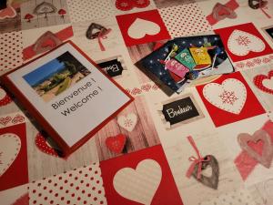 a bed with a bedspread with hearts and a card with a romantic weekend at Appartement chaleureux au cœur des Hautes Vosges in Ventron