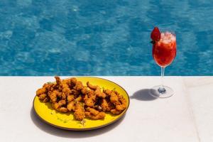 un piatto giallo di cibo e una bevanda accanto a una piscina di Pousada Aldeola by Slaviero Hotéis a Baixio