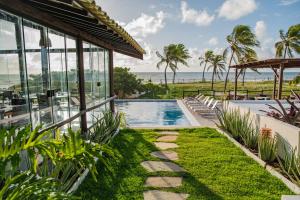 a house with a swimming pool next to the ocean at Pousada Aldeola by Slaviero Hotéis in Baixio