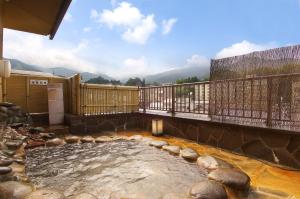 una gran piscina de agua en un balcón con rocas en Ichinoyu Katei, en Yamanouchi
