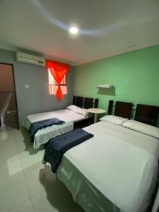 two beds in a room with a red window at Hotel Napoles Valledupar in Valledupar