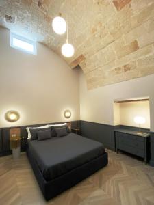 a bedroom with a black bed and a wooden ceiling at Dimore Garibaldi - Puglia Mia Apartments in Monopoli
